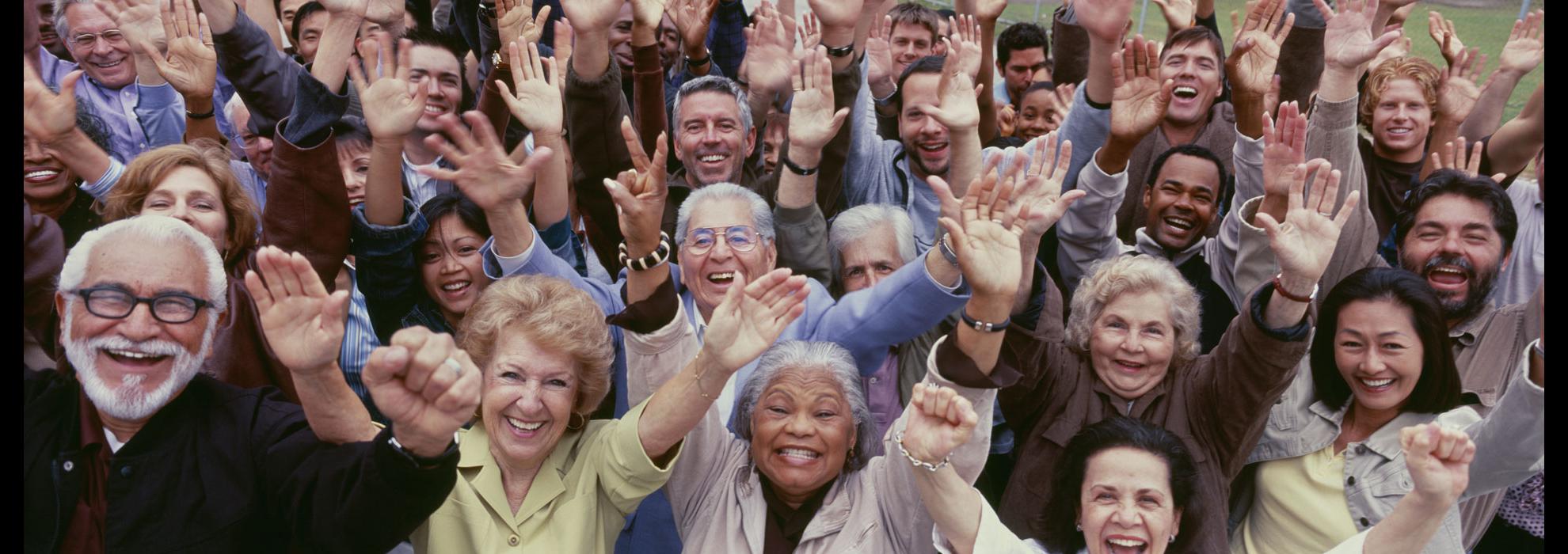 Crowd of people raising both hands to the sky.