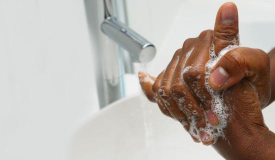 Person washing hands in sink with soap.